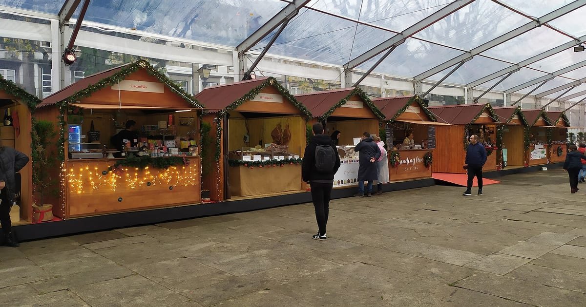 Mercado de Natal iluminado em Braga, com bancas decoradas e luzes festivas no centro histórico durante a quadra natalícia no Minho.