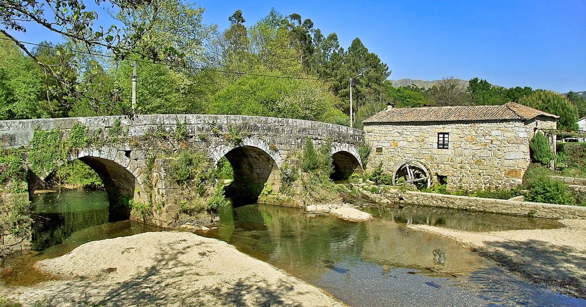 Praia fluvial de Estorãos, em Ponte de Lima, com águas calmas do rio rodeadas de verde, no coração do Minho