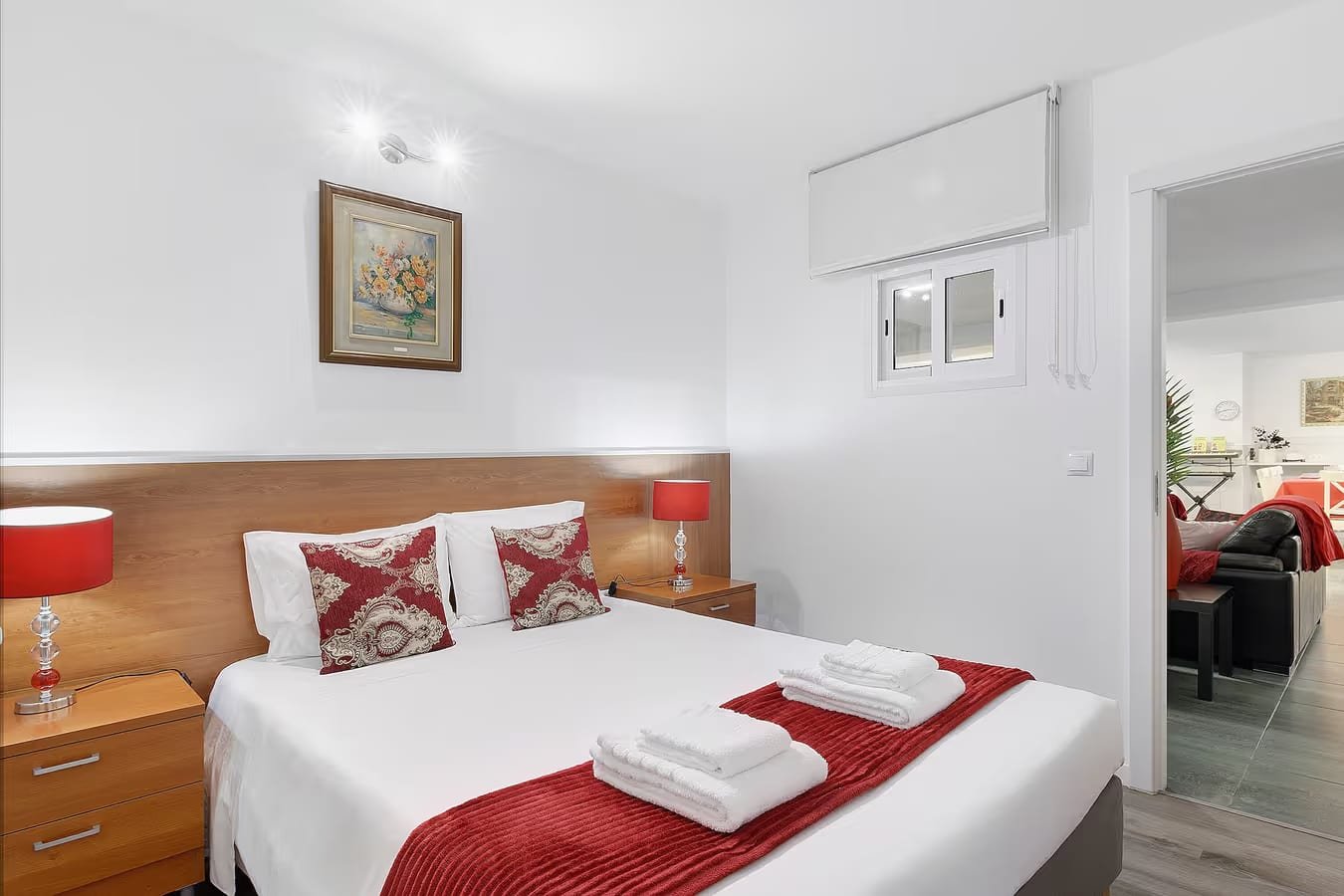 Quarto de casal do Alojamento Rio Neiva em Tregosa, Barcelos, com cama ampla, candeeiros e detalhes vermelhos e acesso ao salão.